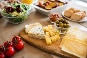 A delicious assortment of cheeses, olives, and fresh tomatoes on a wooden platter, perfect for a gourmet dining experience.